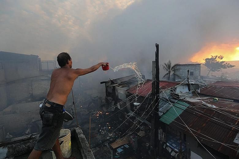 Filipino Fil Binay battles to contain a fire in Mandaluyong City, east of Manila, yesterday. The cause of the fire, which reached the general alarm level, is still unknown.