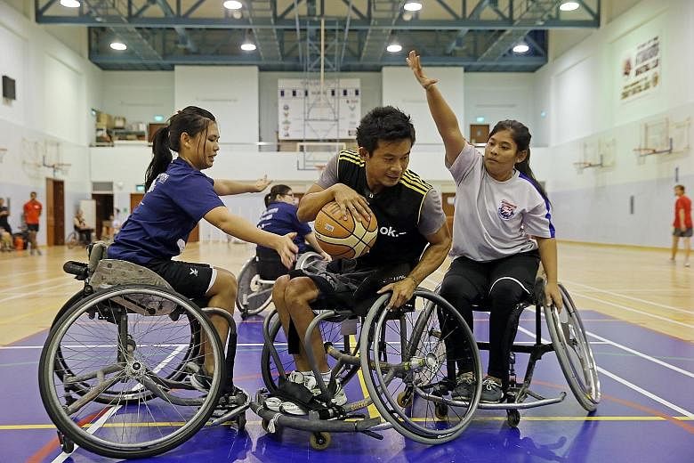 Mr Ng Chong Ping, 42, tries to shield the ball from volunteers Jeannette Leung (left), 25, and Nur Sahira, 24. The team train with a group of able-bodied volunteers, who prove to be tough opponents. Above: Mr Kamas Mohd, 44, gets a rebound while play