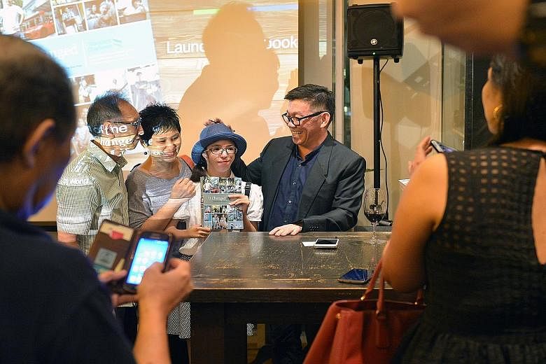 Straits Times senior writer Wong Kim Hoh posing for a photograph with one of his interviewees, photography student Isabelle Lim (second from right), and her parents Nick and Jacqueline Lim, at the launch of his latest book, It Changed My Life, yester