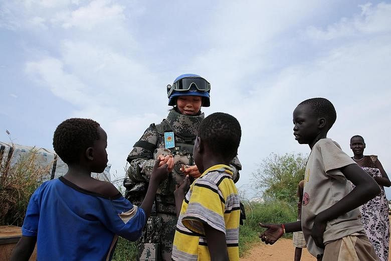 Chinese peacekeeper Jia Xiaochen hands out sweets to children in a refugee camp in Juba, South Sudan. China sent its first peacekeeping infantry battalion to South Sudan in April this year, consisting of 700 peacekeepers. The contingent, which also i