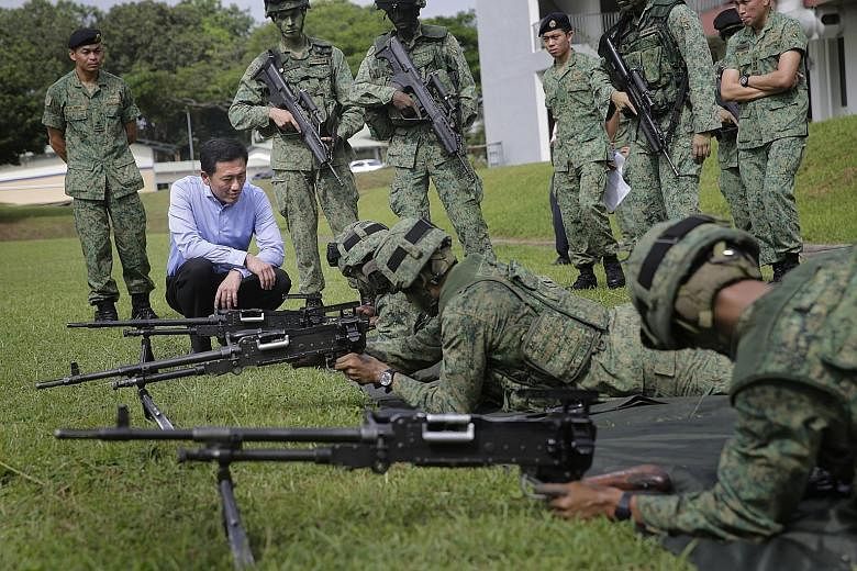 (Far left) Senior Minister of State for Defence Ong Ye Kung watching soldiers at the Amoy Quee Camp executing simulation drills that tested how quickly they can get ready for a mock invasion. (Left) Soldiers responding with a rousing cry as their com