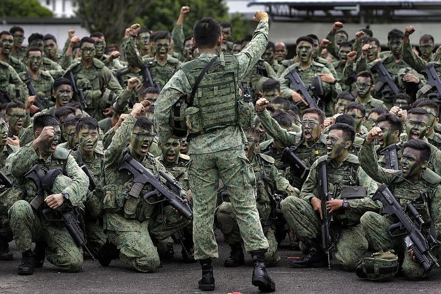 (Far left) Senior Minister of State for Defence Ong Ye Kung watching soldiers at the Amoy Quee Camp executing simulation drills that tested how quickly they can get ready for a mock invasion. (Left) Soldiers responding with a rousing cry as their com