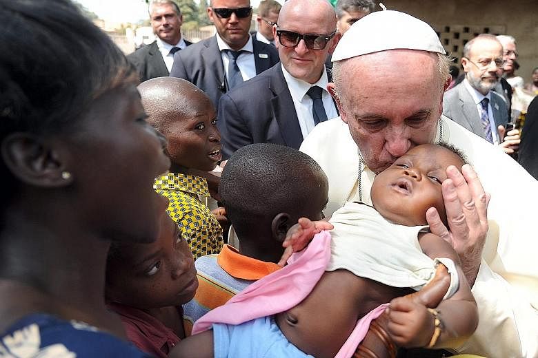 Pope Francis kissing a child during a visit to a refugee camp