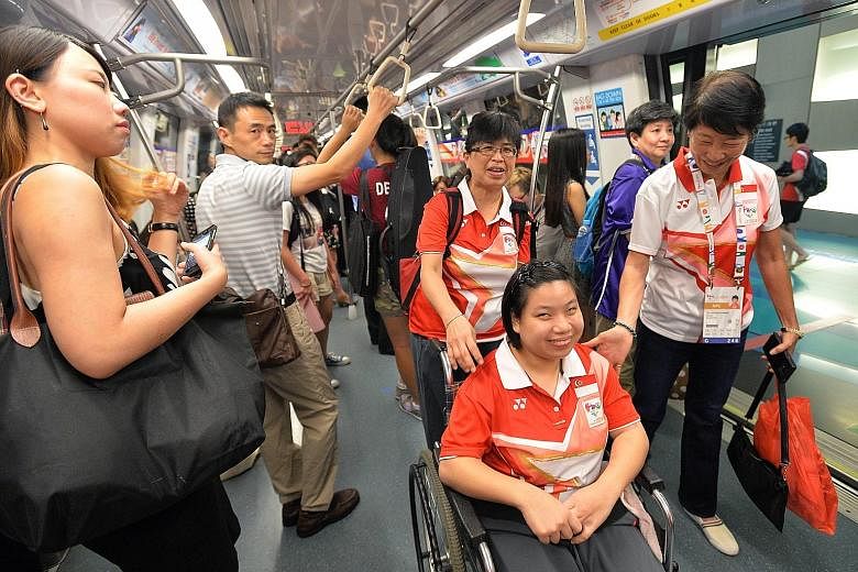 Boccia player Koh Kai Hui (in wheelchair) making her way on the Circle Line from Stadium MRT station to the Games Village at Marina Bay Sands together with Dr Teo-Koh Sock Miang (right), SNPC president, and other officials and athletes.