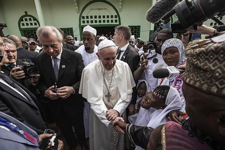 Pope Francis shaking hands with children as he arrived yesterday at the central mosque in the PK5 neighbourhood in Bangui.