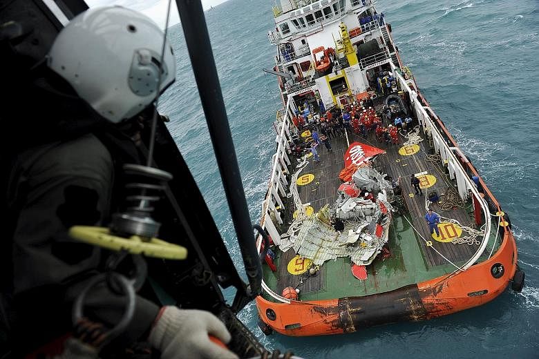 Left: The tail of the AirAsia Flight QZ8501 plane, which crashed on Dec 28 last year, on the deck of rescue ship Crest Onyx. An Indonesian Super Puma military helicopter transferred the tail to the boat after lifting it from the seabed south of Pangk