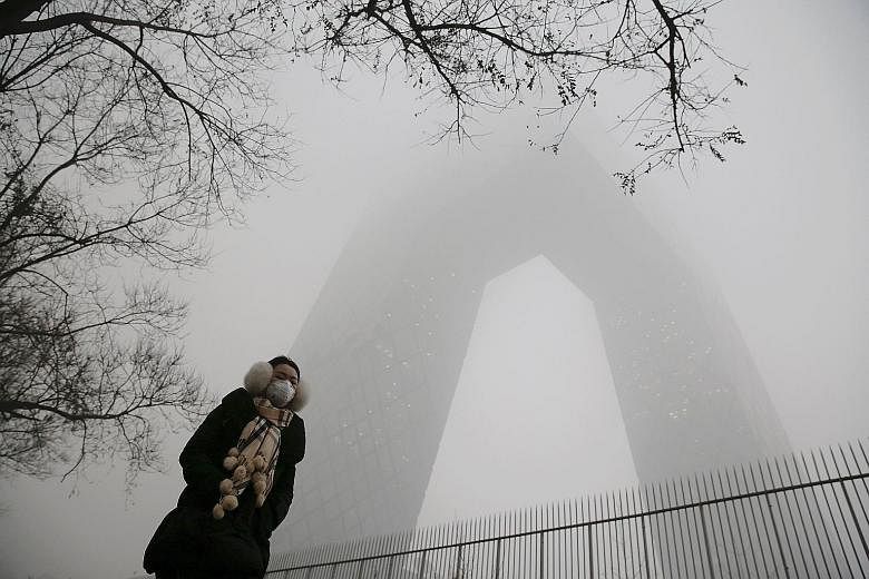 A woman walking past the China Central Television building in Beijing, which was barely visible yesterday. While the Chinese capital often battles with air pollution, the current round of smog is the most severe to hit the city this year. Experts say