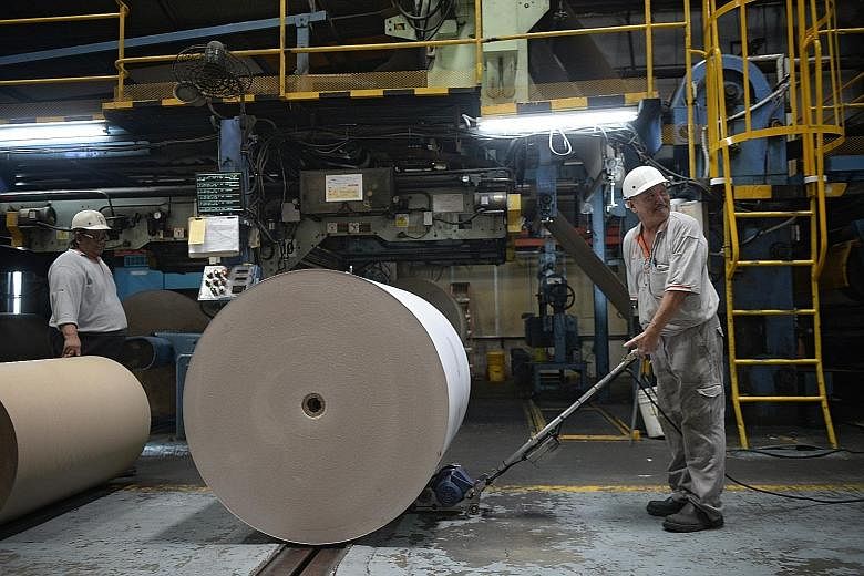 TCG Rengo's machine operator Wan Eng Kok, 60, using a device that helps push paper rolls that often weigh a tonne or more. The company has invested in such equipment to help reduce the manual demands on its older workers.
