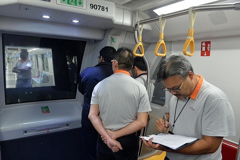 A rescue train being used to push a "stalled" train (left) between the Little India and Newton stations in a simulation of a train breakdown yesterday while SBS Transit staff (right) observe the train recovery exercise.
