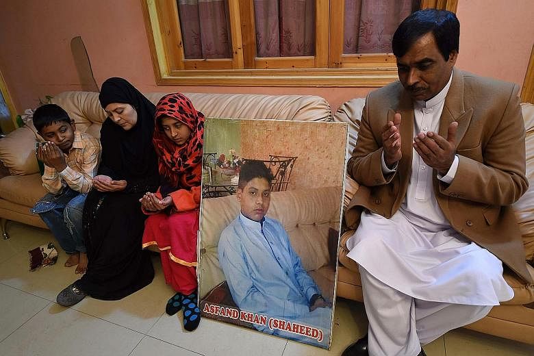 The parents and siblings of slain Pakistani student Asfand Khan, who was killed during an attack by militants at an army public school last year, praying alongside his photo at their residence in Peshawar yesterday. The attack was Pakistan's deadlies