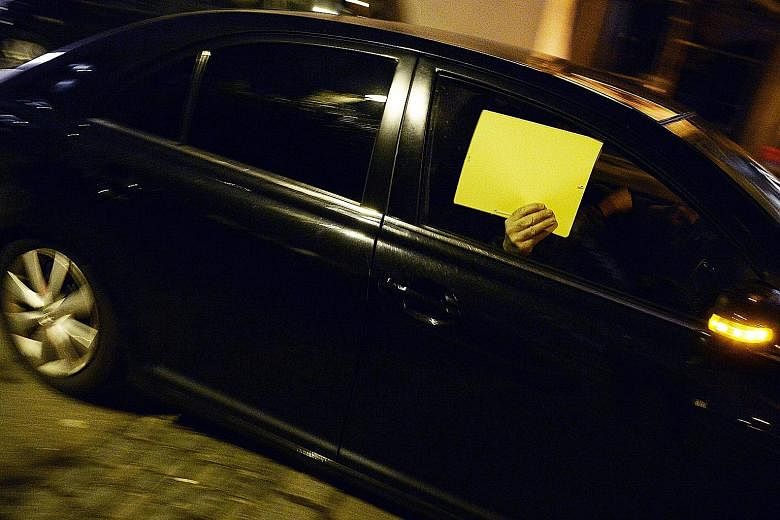 A person hiding behind a folder in a police car near the Baur au Lac hotel in Zurich yesterday, the scene of the dawn raids. Fifa said it will continue to cooperate fully with investigations after police arrested its officials - Juan Angel Napout (be