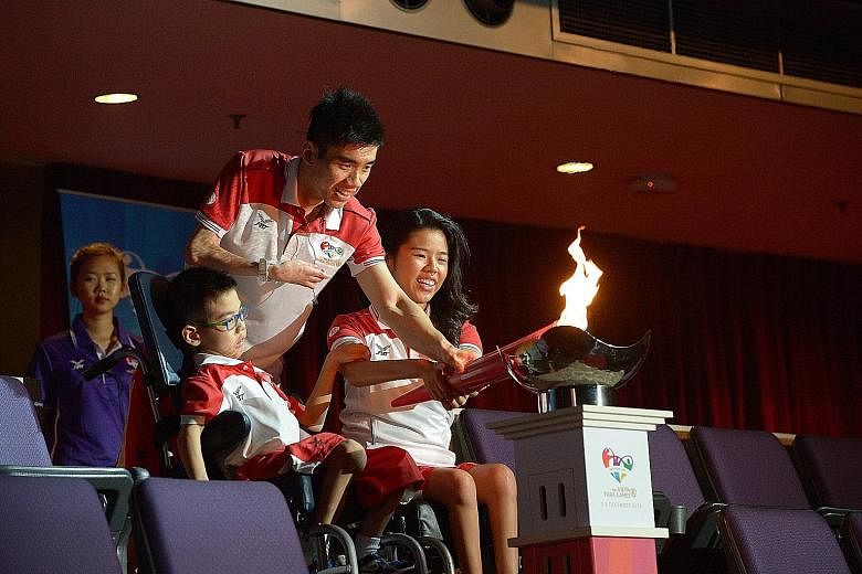 From left: Nine-year-old boccia player Aloysius Gan, badminton player Tay Wei Ming and swimmer Yip Pin Xiu combining to light the Asean Para Games' cauldron at the Singapore Indoor Stadium last night.