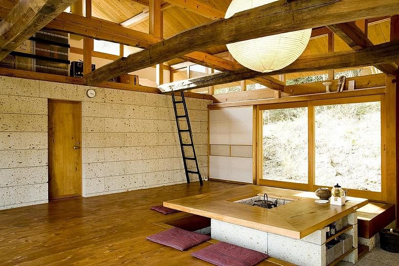 The living room of architect Minoru Matsuzawa has exposed beams. Located in Tochigi, a Japanese prefecture north of Tokyo, the house was built using materials such as oya stone, a local volcanic material, and timber from the forest behind it.