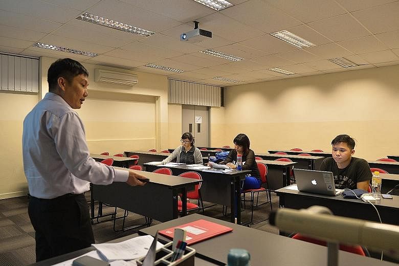 Former M2 students (from left) Ho Yuet Ching, 25, Yii Yieng Hong, 26, and Leon Lee, 25, attending a lesson on consumer protection conducted by former M2 lecturer Francis Ho, 40, at PSB Academy last month.