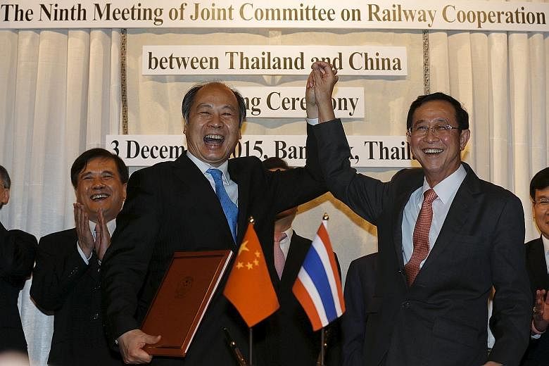 Mr Wang Xiaotao (left), the deputy head of China's National Development and Reform Commission, and Thai Transport Minister Arkhom Termpittayapaisith (right) celebrating the railway construction agreement. The deal underlines the warming ties between 