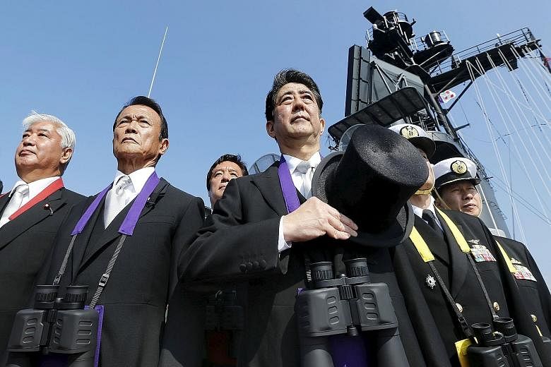 Japanese Prime Minister Shinzo Abe (far right) reviewing the Japan Maritime Self-Defence Force fleet with Deputy Prime Minister and Finance Minister Taro Aso (centre) and Defence Minister Gen Nakatani at Sagami Bay, south of Tokyo, on Oct 18.
