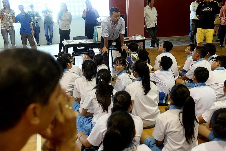 A teacher speaks to pupils before the PSLE results are handed out. Some parents set the bar too high and end up reacting badly when their children fail to meet their lofty expectations.