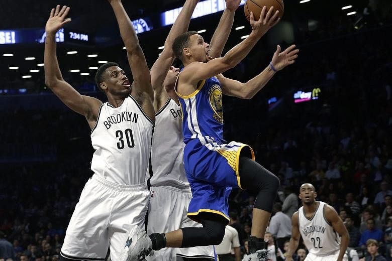 Stephen Curry (right) of the Golden State Warriors drives past Brooklyn Nets opponents Thaddeus Young (No. 30) and Brook Lopez during the Warriors' 114-98 victory at the Barclays Center on Sunday.