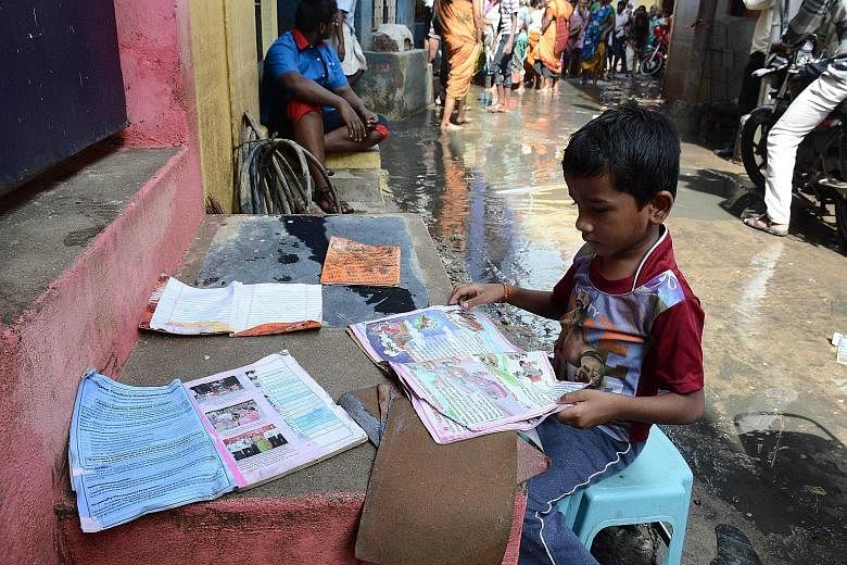 An Indian boy putting out his school books to dry as floodwaters receded in Chennai on Monday. Residents in India's southern Tamil Nadu state are grappling with the aftermath of the devastating floods as the authorities step up relief work, following