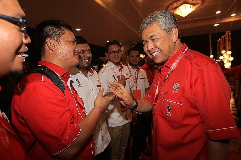 Deputy Prime Minister Ahmad Zahid Hamidi (right), an Umno vice-president, greeting some of the delegates attending the party's general assembly that started yesterday.
