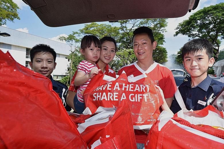 Prudential agent Thomas Lee, 43; his wife Shalyn, 31; and their three-year-old daughter Adelia delivered hampers last Saturday as part of the Boys' Brigade Share-A-Gift project. With them are Boys' Brigade members Lemuel Fan Wenle (left), 14, and Jov
