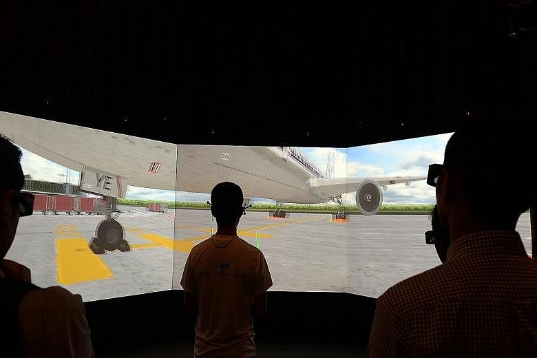 Nanyang Polytechnic students demonstrating how the 3D immersive virtual reality centre provides a virtual airport environment.