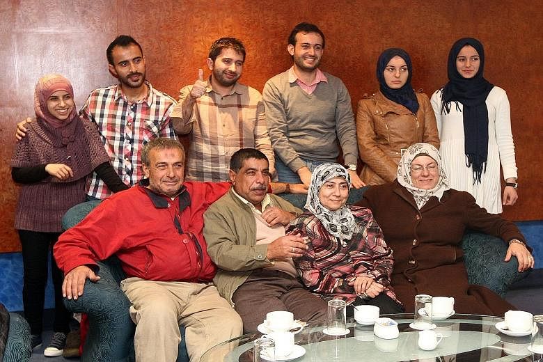 Syrian hairstylists Mohamed Ibrahim (back row, third from left) and Ali Abdul Naser (back row, fourth from left) with their families who arrived in Kuala Lumpur on Tuesday from Turkey. The families are the first batch of Syrians who are in Malaysia a