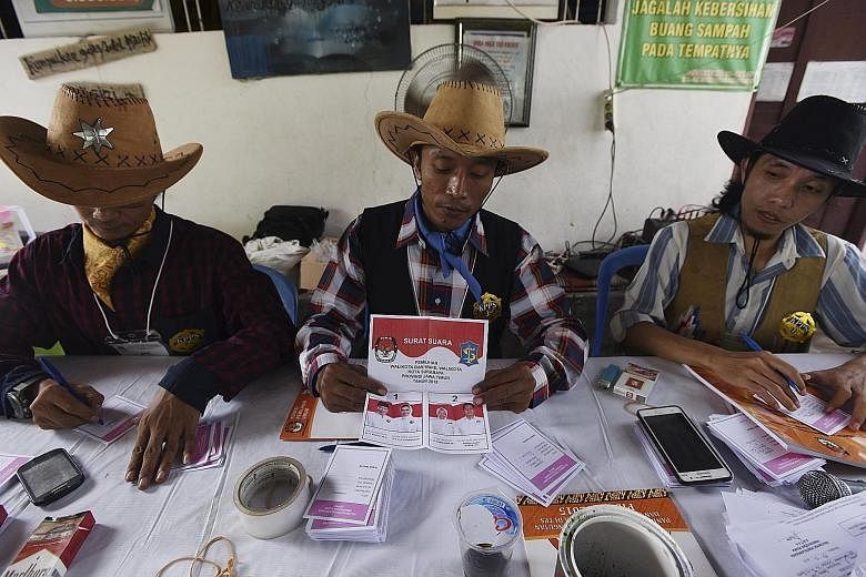 Officials in cowboy costumes preparing ballot slips at a polling station in Surabaya, East Java, yesterday. The decision to hold the regional elections on the same day was aimed at cutting costs and boosting efficiency.