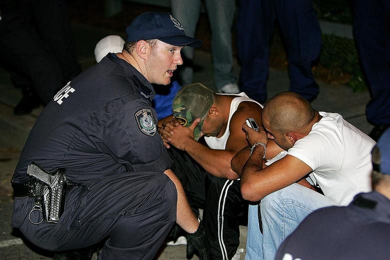A policeman watching over detained youths at South Sydney's Cronulla beach on Dec 12, 2005, during a second night of racial violence in Sydney. The alcohol-fuelled riots pitted "Anglo" nationalists against the Middle-Eastern community. An estimated 5