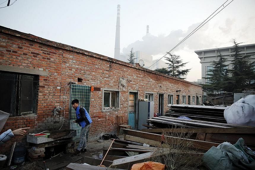 A worker brushing his teeth outside his dwelling, which is next to a coal power plant, in Beijing during smog-free weather yesterday, which was the day the city's red-alert measures expired.
