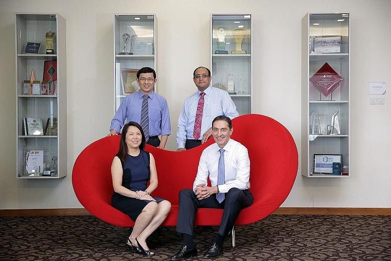 These National University Hospital doctors are among medical professionals from overseas who have made Singapore home. Dr Koh Liang Piu (standing, left), originally from Malaysia, and Associate Professor Theodoros Kofidis (seated) from Greece are now