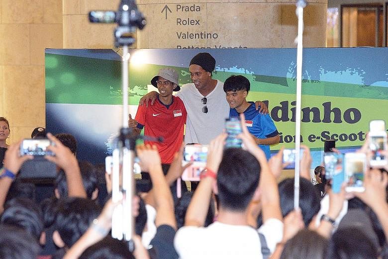 Ronaldinho posing with his fans (left) at Ion Orchard as he launched his E-scooter brand together with his football academy. The player, known for his dribbling skills and deft flicks, leaving Ion Orchard on a chauffeured Rolls Royce (left).