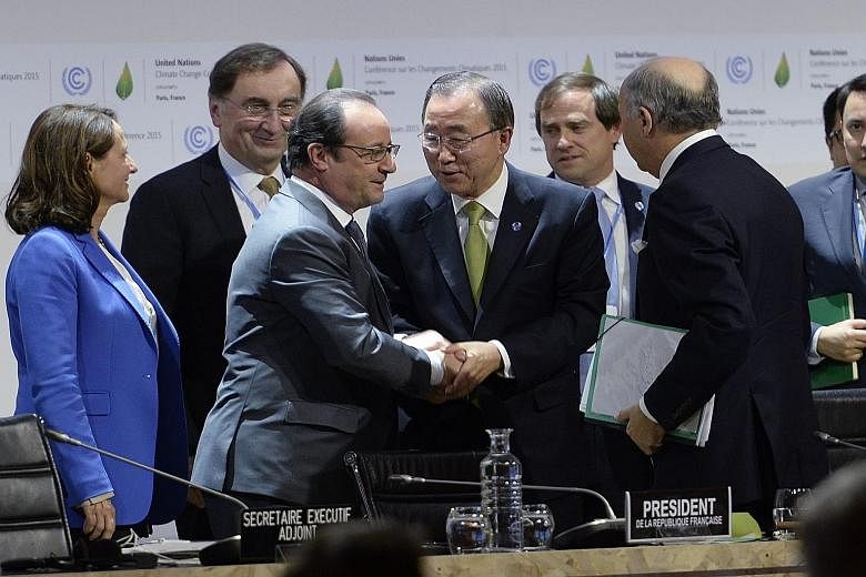 French President Francois Hollande shaking hands with UN Secretary-General Ban Ki Moon at the Paris climate summit yesterday. On the right, holding files, is French Foreign Minister Laurent Fabius.