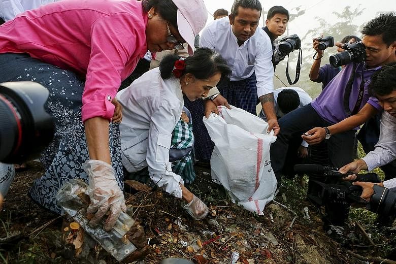 Myanmar's pro-democracy leader, Ms Aung San Suu Kyi, helping to collect rubbish in Kawhmu township, on the outskirts of Yangon, yesterday.