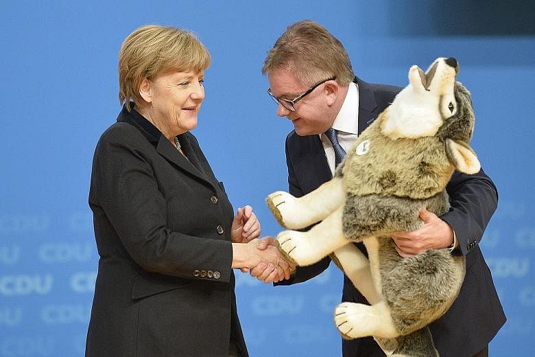 German Chancellor and leader of the Christian Democratic Union Angela Merkel receiving a toy from Mr Guido Wolf, the party's top candidate in the upcoming state elections in Baden-Wurttemberg, where the CDU staged a show of unity at a pivotal congres