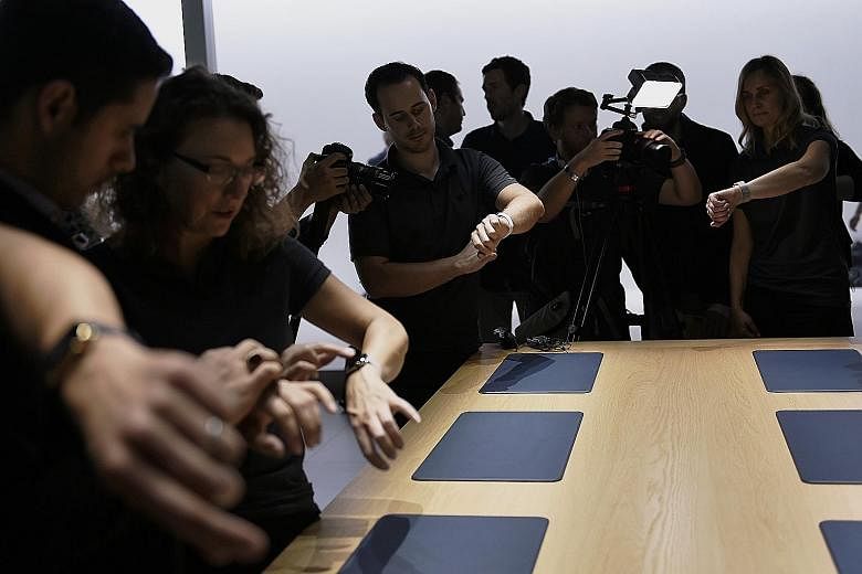 Attendees trying on the Apple Watch during an event. A report commissioned by the Singapore Exchange on top digital trends, released yesterday, noted that the growth of tech wearables, which include electronic technologies or computers incorporated i