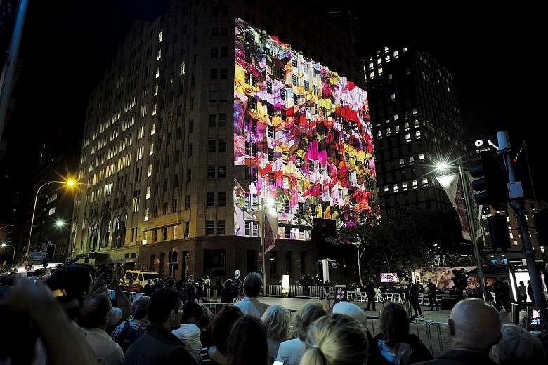A giant photo of floral tributes to the victims of the Sydney cafe siege being projected onto the exterior wall of the Lindt Cafe during a memorial service yesterday marking the first anniversary of the incident.