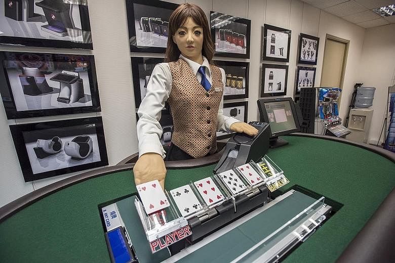 Min, a prototype human-like electronic croupier, dealing a card during a demonstration at the headquarters of Paradise Entertainment in Macau yesterday. Paradise, a Hong Kong-based gaming machine manufacturer and supplier, says the robot could cut la