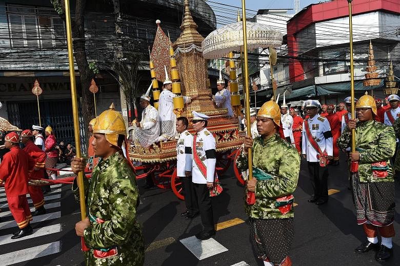 Thousands of Thais (left) holding photos of the kingdom's late Buddhist leader lined the streets yesterday as a carriage (above) carrying an urn containing his remains was driven through Bangkok.