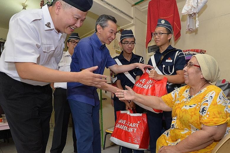 Boys' Brigade president Ho Yew Kee (at left) and Share-A-Gift 2015 chairman Lui Chong Chee (centre) giving Madam Zainubi Abdul Majid two food hampers yesterday. She said she was "very grateful to receive these gifts".