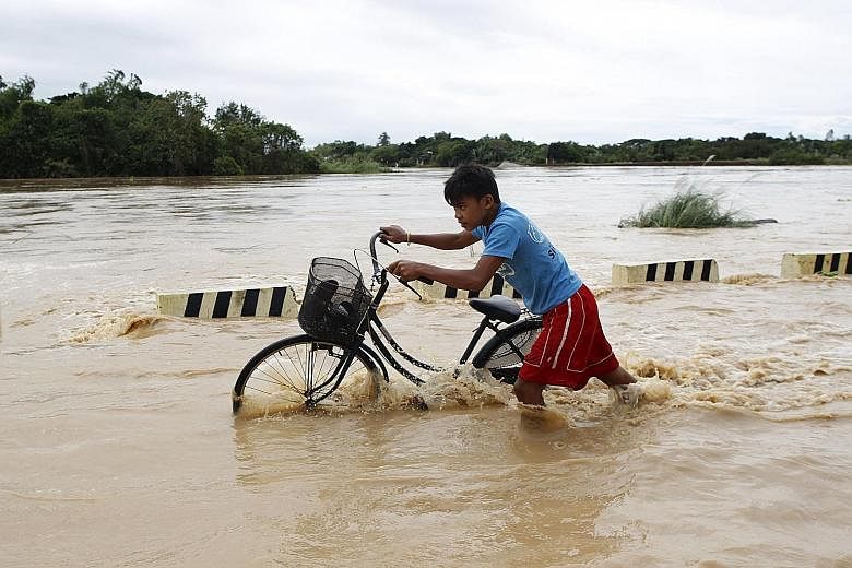 A boy making his way through a flooded road after heavy rain in Pampanga province, north of Manila, on Thursday. Nine people were killed and hundreds spent the night huddled on their roofs in the central Philippines as floods generated by a powerful 