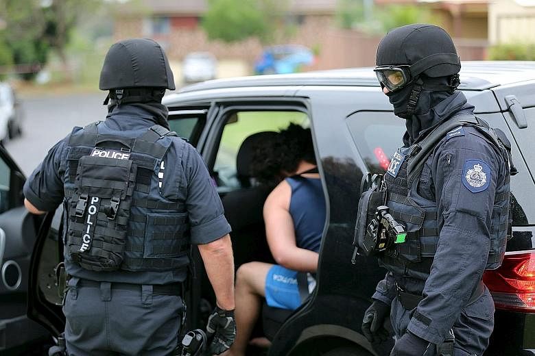Heavily armed police detaining a man in Sydney on Dec 10. Australian police said they had charged a 20-year-old man and a 15-year-old boy with conspiracy to conduct an act of terrorism after they were arrested during the early-morning raids. In the p