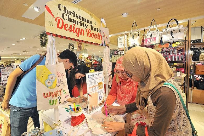(From left) Salesman Vernard Ong, 30, his girlfriend, accountant Chrys Ng, 26, housewife Imas Nur Tjahyawati, 48, and student Ulfy Fitryani, 18, designing totes they bought at BHG at Bugis Junction yesterday. As part of BHG's Christmas Charity Tote i