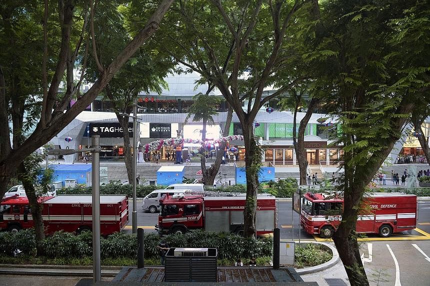Singapore Civil Defence Force officers (left) on the second floor of Lucky Plaza, where they put out a lunchtime fire yesterday at an Indonesian restaurant using three water jets, and (below, from left) an SCDF support vehicle and two fire engines ou