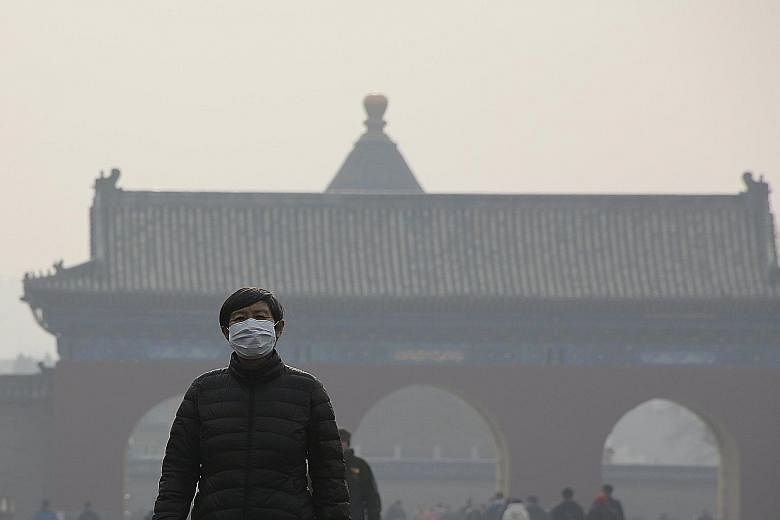 A visitor to the smog-shrouded Temple of Heaven park in Beijing taking the weather station's advice to heart and wearing a protective mask yesterday.