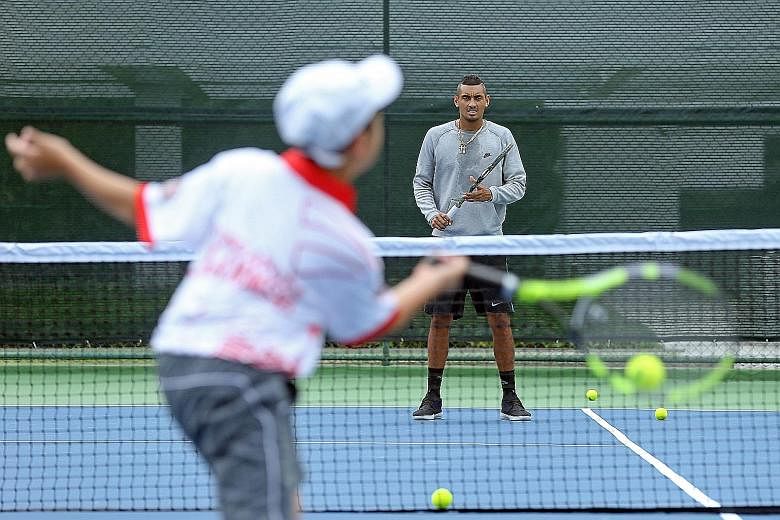 Australia's Nick Kyrgios , (facing camera), who plays for the Singapore Slammers, conducting a clinic for juniors at the Marina Square rooftop court yesterday.