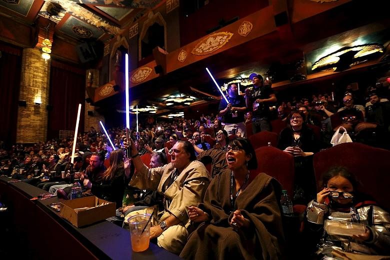 Moviegoers, eager to see the first Star Wars movie in a decade, cheering and waving light sabers before the first screening of The Force Awakens at the TCL Chinese Theatre in Hollywood, California, on Thursday.