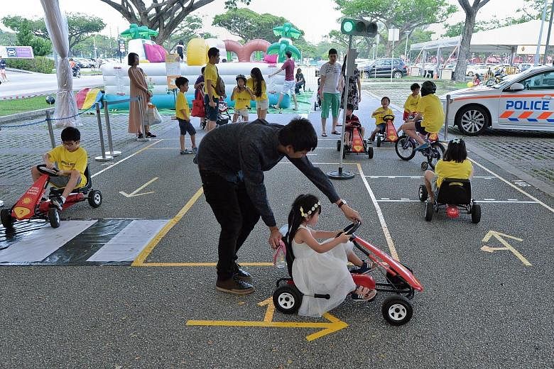 Children learning basic traffic rules at a road-safety circuit at the AAS carnival held at Carpark 5 at Kallang Leisure Park yesterday.
