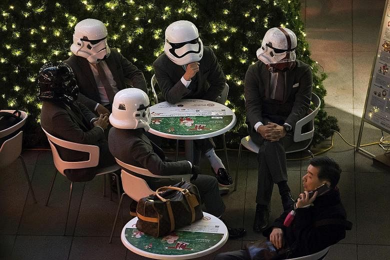 Fans wearing Stormtrooper helmets in a food court ahead of the first public screening of The Force Awakens in Roppongi Hills in Tokyo. Fans posing with members of Malaysia's Star Wars Fan Club dressed as various characters before watching The Force A