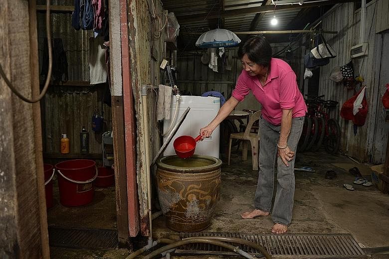 Pulau Ubin resident and bicycle rental shop owner Yang Hui Qing, 60, scooping water, which came from a well, for cooking yesterday. She boils the water first before using it.